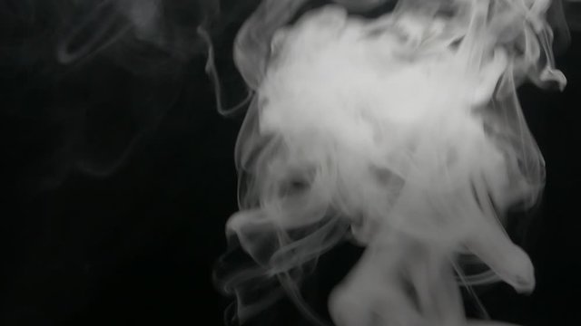 Smoking electronic cigarette. Closeup vapor floating in air on black background. Real dry smoke clouds fog overlay.