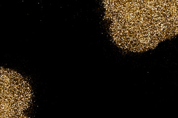 Golden glitter formed in spots on a deep black surface. Christmas, new year, birthday, special occasions background, with a copy space.