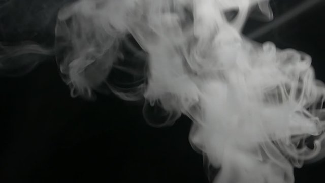 Smoking electronic cigarette. Closeup vapor floating in air on black background. Real dry smoke clouds fog overlay.