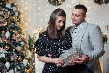 True feelings, happiness! Lovely, sensual cute brunette lady, winter. Fashion photo of tender couple posing at studio. Merry Christmas and Happy New Year. Happy pair hold a New Year's gift