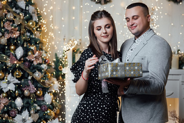 True feelings, happiness! Lovely, sensual cute brunette lady, winter. Fashion photo of tender couple posing at studio. Merry Christmas and Happy New Year. Happy pair hold a New Year's gift
