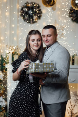 True feelings, happiness! Lovely, sensual cute brunette lady, winter. Fashion photo of tender couple posing at studio. Merry Christmas and Happy New Year. Happy pair hold a New Year's gift