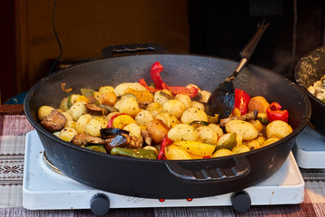Fried potatoes in a large frying pan. Grilled vegetables on festival background.