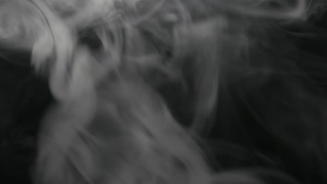 Smoking electronic cigarette. Closeup vapor floating in air on black background. Real dry smoke clouds fog overlay.