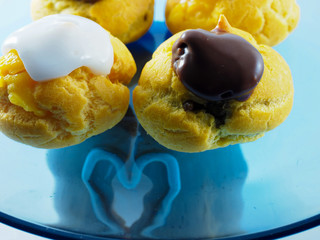 four profiterolle close up with cream and chocolate