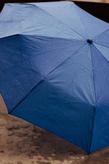 Rain drops on open umbrella, blue color, umbrella on the ground.