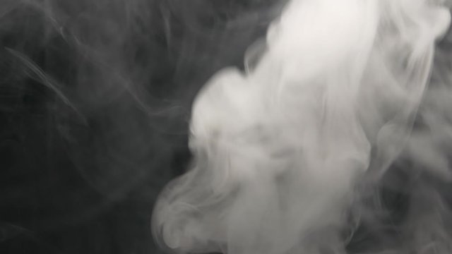 Smoking electronic cigarette. Closeup vapor floating in air on black background. Real dry smoke clouds fog overlay.