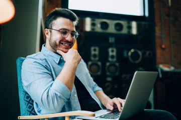 Cheerful man watching funny content on laptop