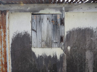 Closeup of rusty wooden window on white and black wall. Traditional architecture of the Antilles....