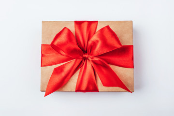 Cardboard gift box with red bow on white background.