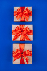 Three cardboard gift boxes with bows on blue background.