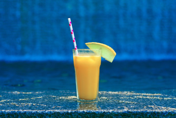cocktail of pineapple, mango and passion fruit juice with ice on water background
