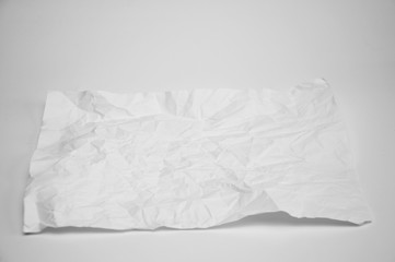 Crumpled sheet of paper lies on a table on a white background.