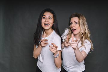 Cheerful friends pointing with fingers
