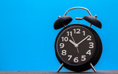 Bell Clock black color on wood with blue background,copyspace