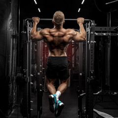 Fototapeta na wymiar power muscular bodybuilder guy doing pullups in gym. Fitness man pumping up lats muscles. Fitness and bodybuilding training health lifestyle concept