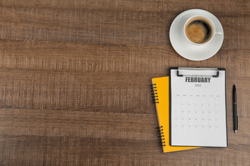 Flat lay composition with calendar and cup of coffee on wooden table. Space for text