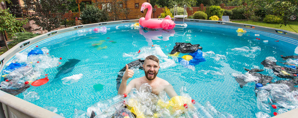 Problem of trash, plastic recycling, pollution and environmental concept - silly man swim and have fun in a polluted pool. Bottles and plastic bags float near them - obrazy, fototapety, plakaty