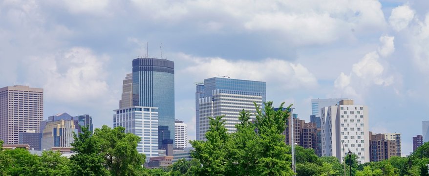 Blue sky with clouds over the Minneapolis skyline and green trees
