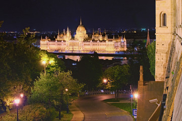 Night lights landscape of Budapest. Astonishing view of illuminated Hungarian Parliament Building. View from Fisherman's Bastion. Winding road with lanterns through the park in the foreground