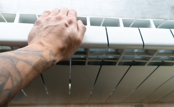 Arm With Tattoo Warming In Indoor Central System Heater. Hand Checking Temperature And Touching The Thermostat. Interior Radiator In The Apartment