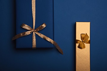 Two gift boxes wrapped in classic blue and golden paper with a gold ribbon. Color of the year 2020, Classic Blue. Copy space.