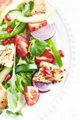 Healthy Salad with Pomegranate seeds, Chicken Briest, Green Pepper and fresh Basil. Close up. Top view. 