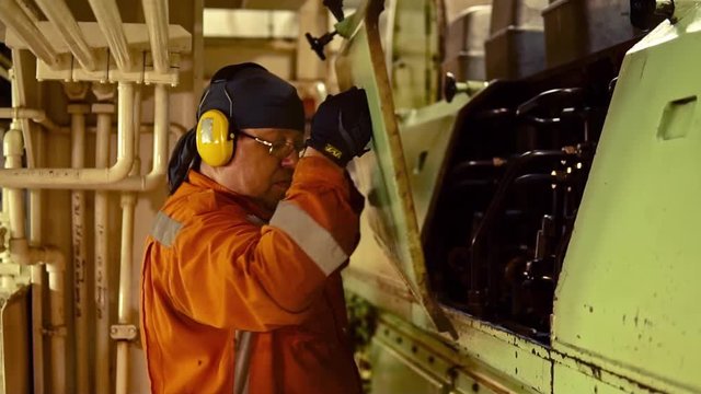 Marine engineer inspecting ship's engine in engine control room ECR. Seamen's work.