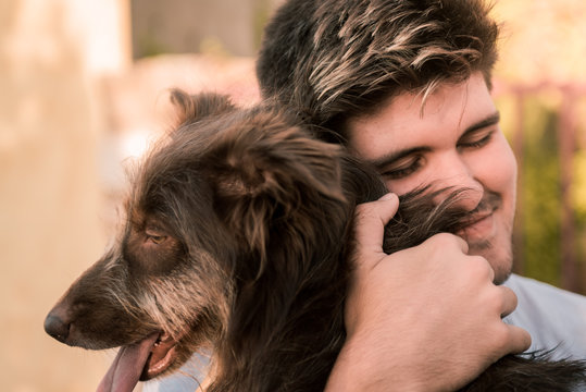 Stock photo of a young man hugging a brown dog, friendly concept animal, best friends.