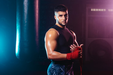 young and muscular man wrapping his hands with boxing hands tape - fight, sport and boxing themes