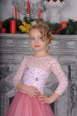young girl in a pink dress by the fireplace