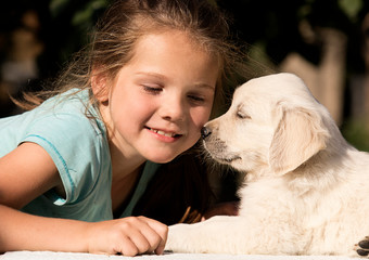 smiling baby girl and golden retriever puppy together