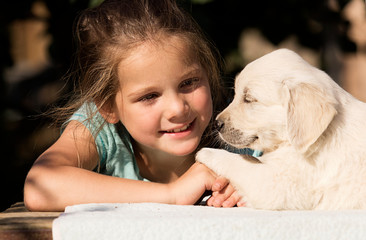 smiling baby girl and golden retriever puppy together