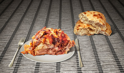 Freshly Spit Roasted Crunchy Pork Shoulder and Domestic Pita Bread Loaf Set on Paper Parchment Vignette Backdrop