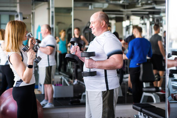 Happy older married couple doing exercises with dumbbells.
