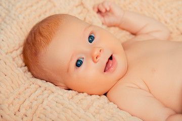 Newborn lying on a soft cream plaid with copy space for text or advertising. studio shot. beautiful Caucasian child. Looking at camera. Motherhood.   