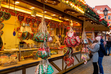 Naklejka premium Young woman walking on Christmas market in Europe on holidays. Gingerbread shop and Christmas toys at Xmas Market