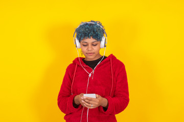 afro american girl with mobile phone and headphones on yellow background
