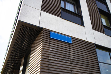 Address plate on the corner of the house. Empty street sign. View of new modern apartment house....