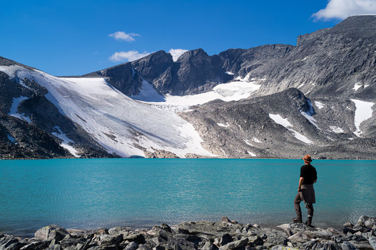 Man looking at a glacier near a lake in the Dovre mountains, Norway. © ajwk