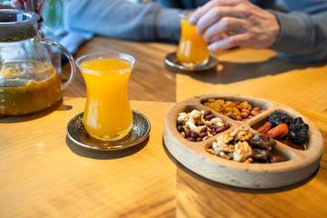 A man eats nuts and drinks tea in cafe. Wooden plate with nuts and dried fruits. Turkish sweets.