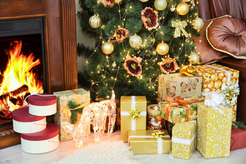 Golden Christmas gifts near Christmas fir-tree taken closeup. Ne