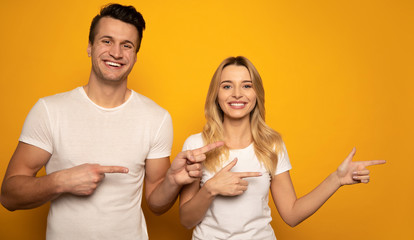 One way. A perfect couple is posing on a yellow background, in white t-shirts, both pointing to the...