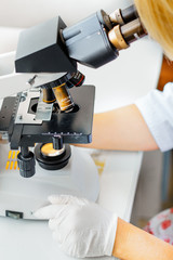 The lab technician looks into the microscope and records and analyzes the blood.