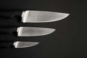 Modern Kitchen Knives Set with a black handles on Dark Background. Black knives on a black background. Chef's Knives Concept.