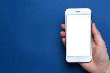 Mobile phone in hand on a classic blue background with copyspace. Trendy Pantone color 2020