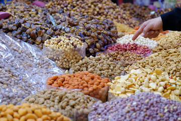 Dried fruit stand at a food market in Morocco with hand pointing at the nuts