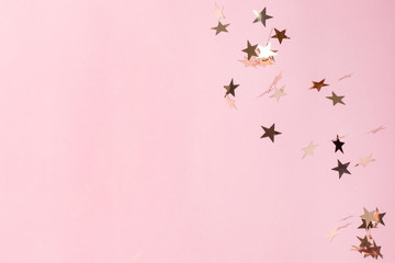 Silver star confetti on pastel pink background. Bright and festive holiday background.