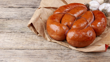 Smoked sausages on a wooden board wrapped in the paper