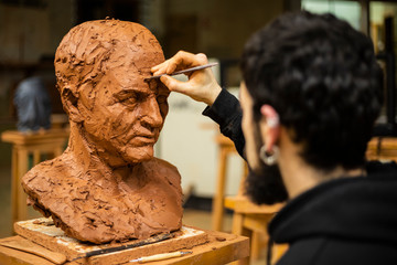 Sculptor finishing a clay head - obrazy, fototapety, plakaty